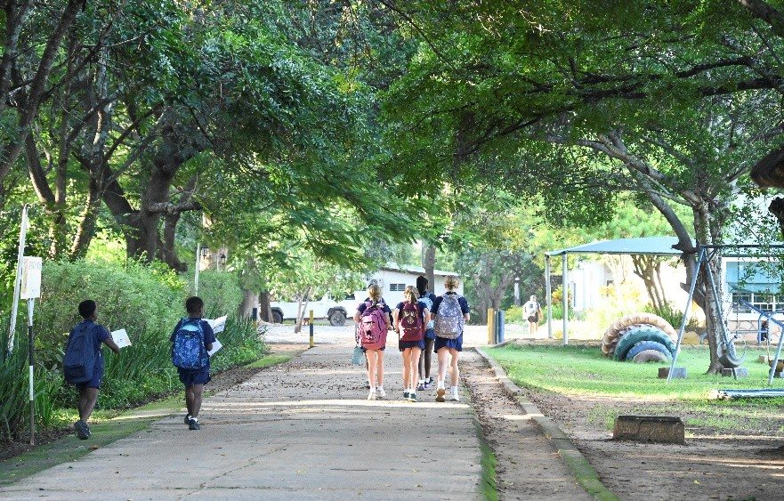 Children walking to class along a tree-lined path on the Musikili campus